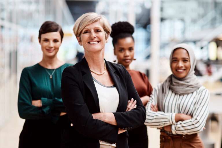 A group of four diverse women standing together with their arms folded