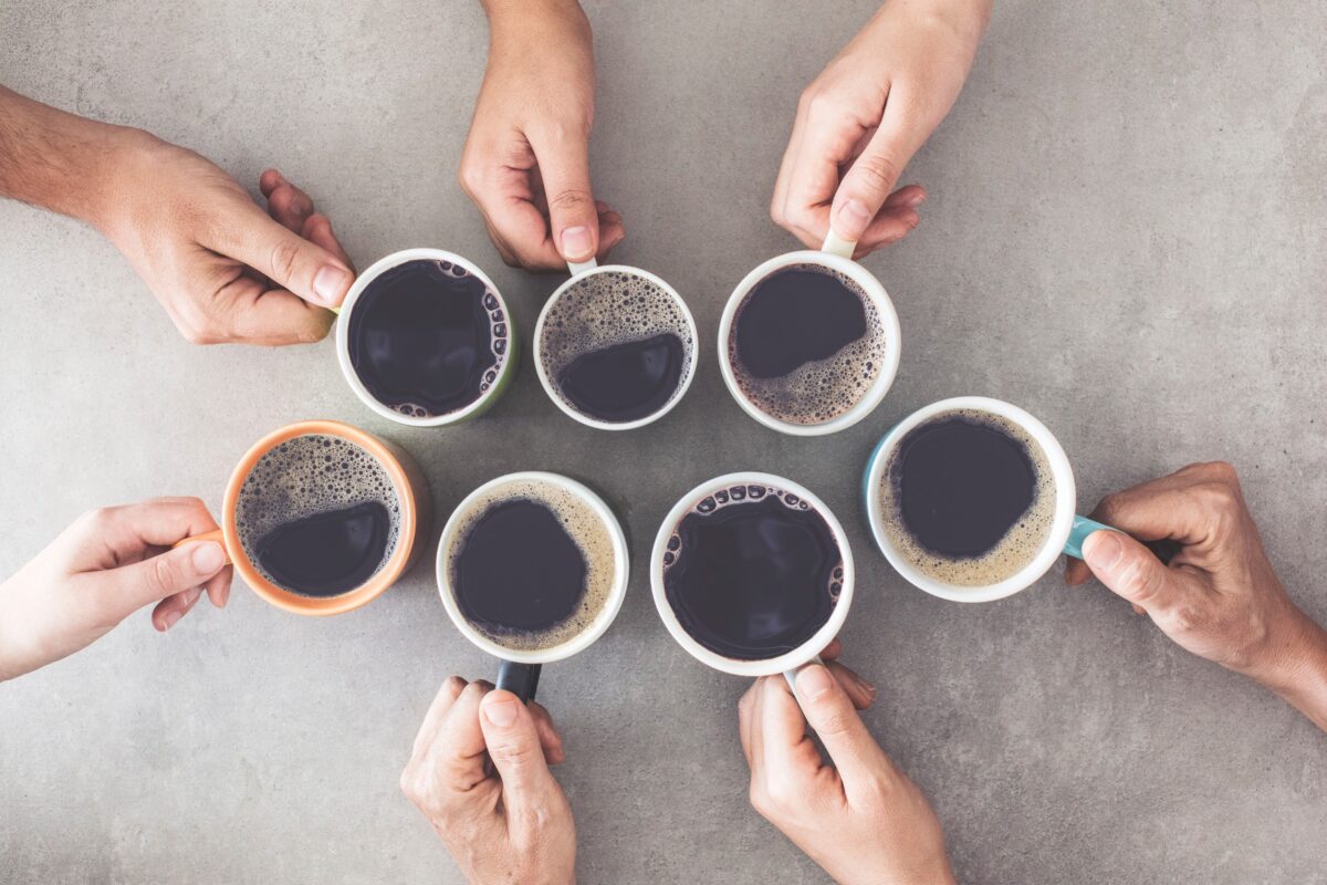 Seven people clinking coffee cups together