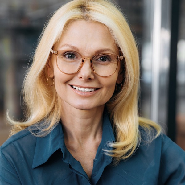 Professional headshot of a middle-aged woman with blond hair and glasses