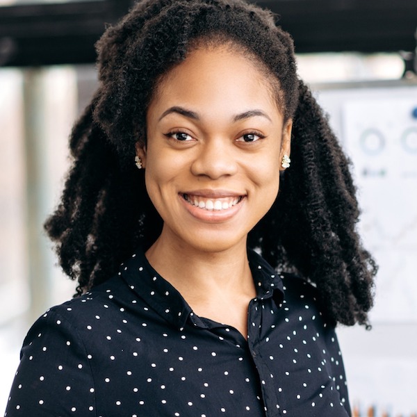 Professional headshot of a young African American woman wearing a blue and white polka dot shirt
