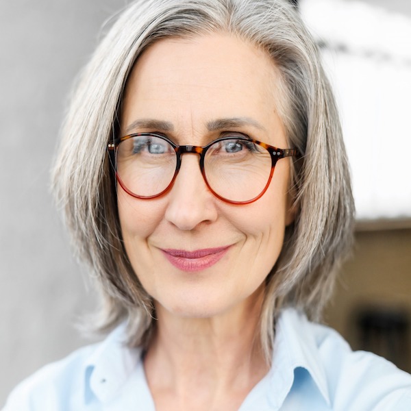 A headshot of an older woman with gray hair and glasses