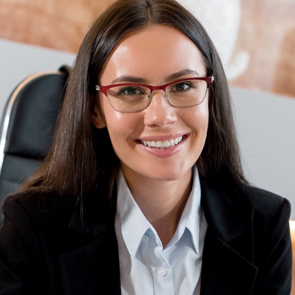 Headshot of a woman with brown hair and glasses in a suit