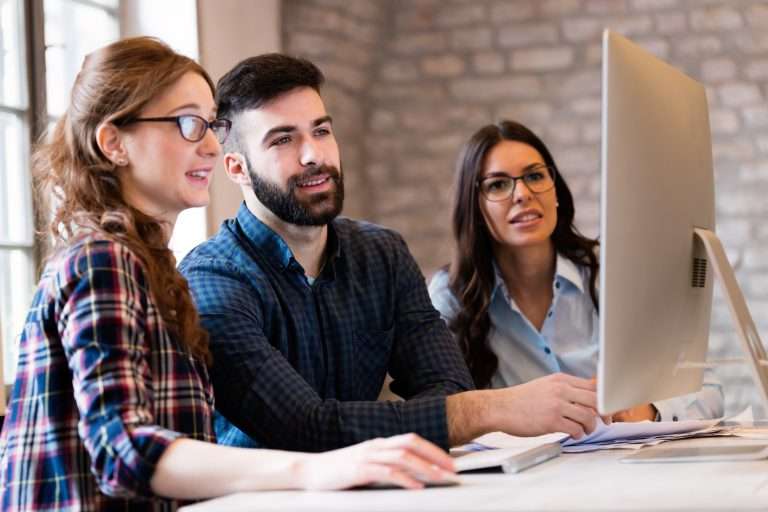Three coworkers working together on a computer