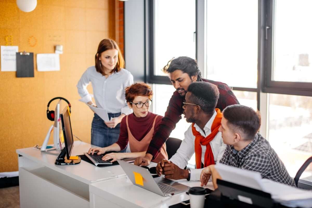 A team of two women and three men working together in the office
