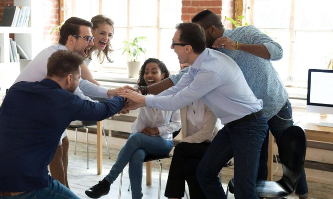 A group of six coworkers putting their hands together in a circle