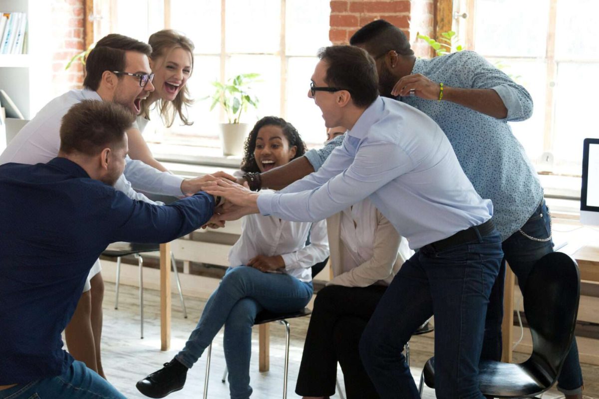 A group of six coworkers putting their hands together in a circle