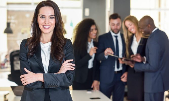 A woman standing in front of her team of employees while they work