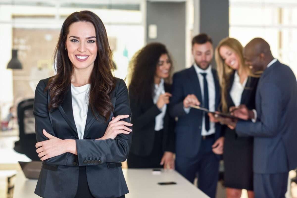 A woman standing in front of her team of employees while they work