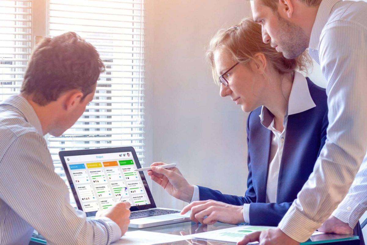 A woman and two men looking at work charts on a computer