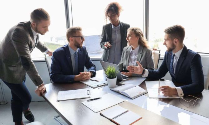 Three men and two women gathered around a table discussing