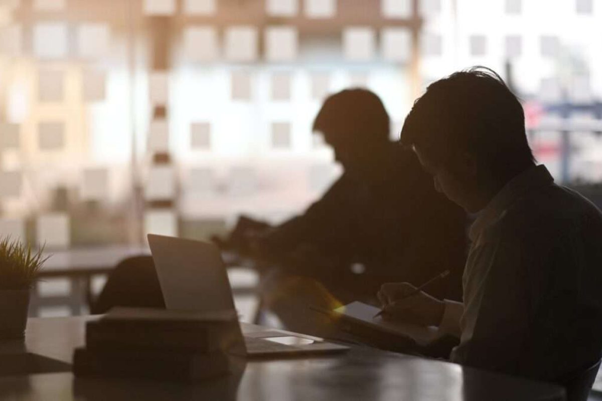 The outlines of two men working separately at their desks