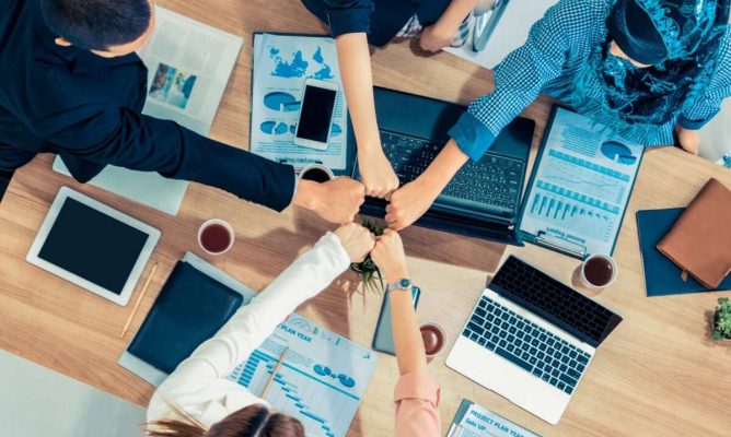 A team at work putting their hands together in a circle to celebrate success