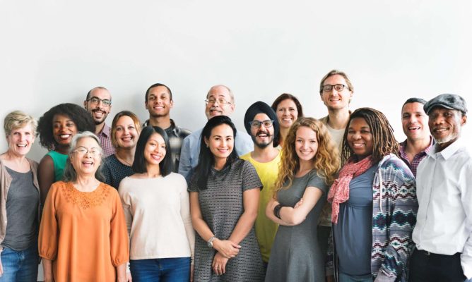 A large group of women and men of all races standing together and smiling