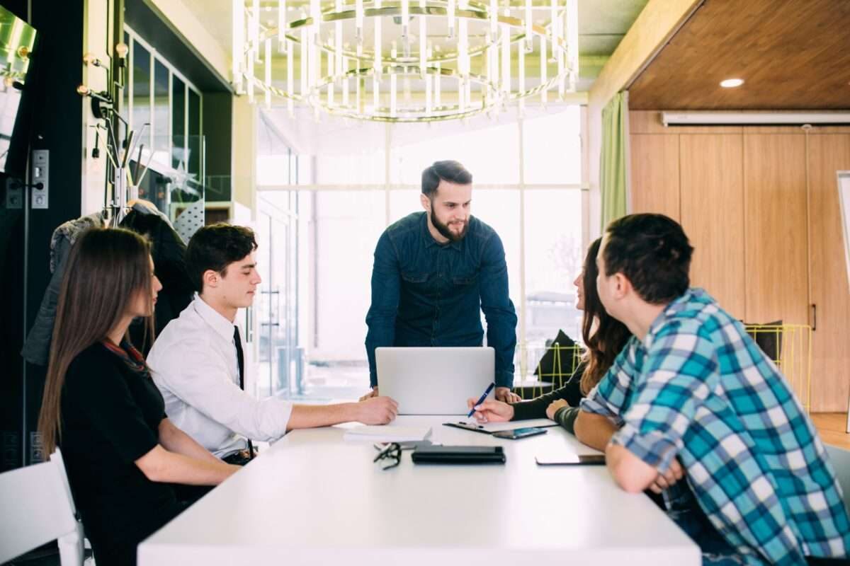 A man leading a team meeting with four other employees