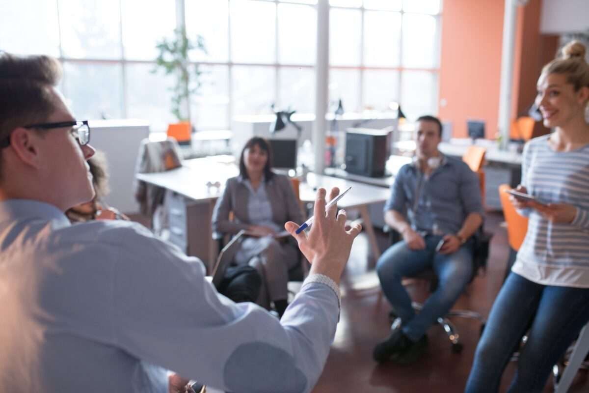A man leading a discussion with two women and a man listening