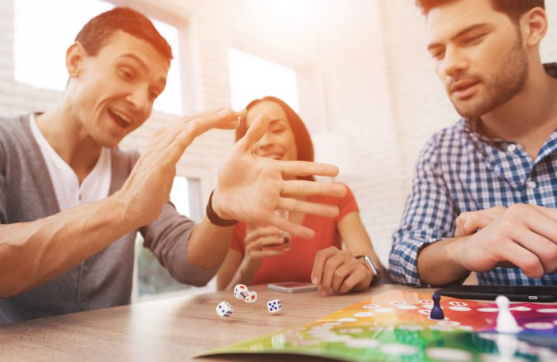 Two men and a woman playing a board game together