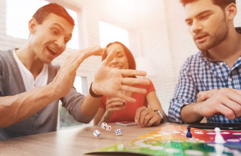 Two men and a woman playing a board game together