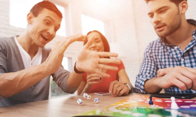 Two men and a woman playing a board game together