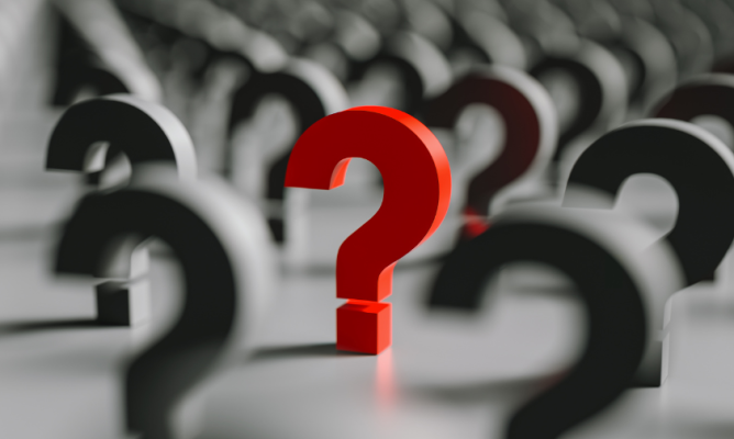 Many gray question marks resting on a flat surface with one red question mark in the center