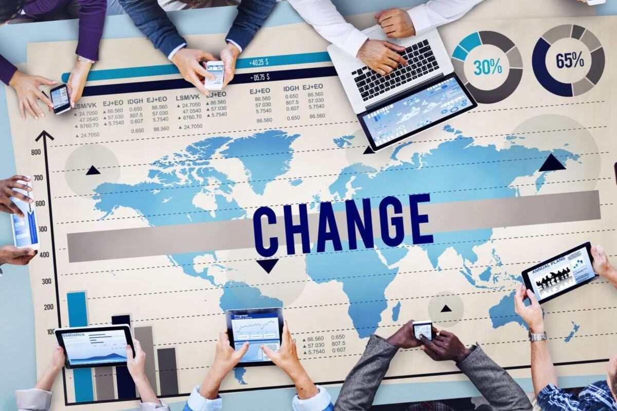 People working around a table with a map of the world spread across and change written on it