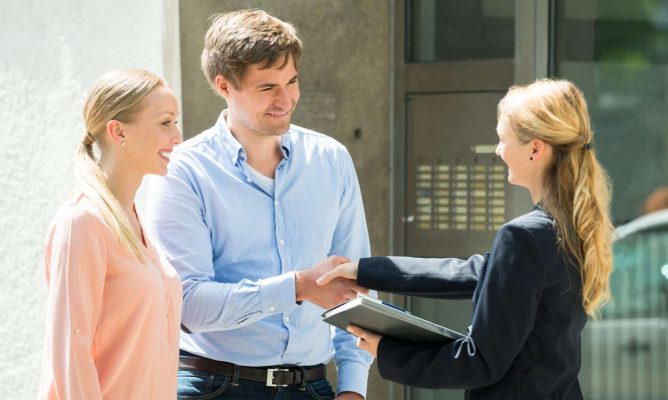 A woman shaking hands with a man who has a woman standing next to him