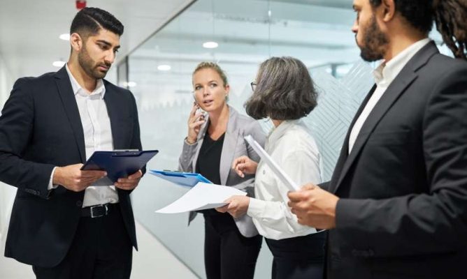 Two men and two women talking in an office hallway
