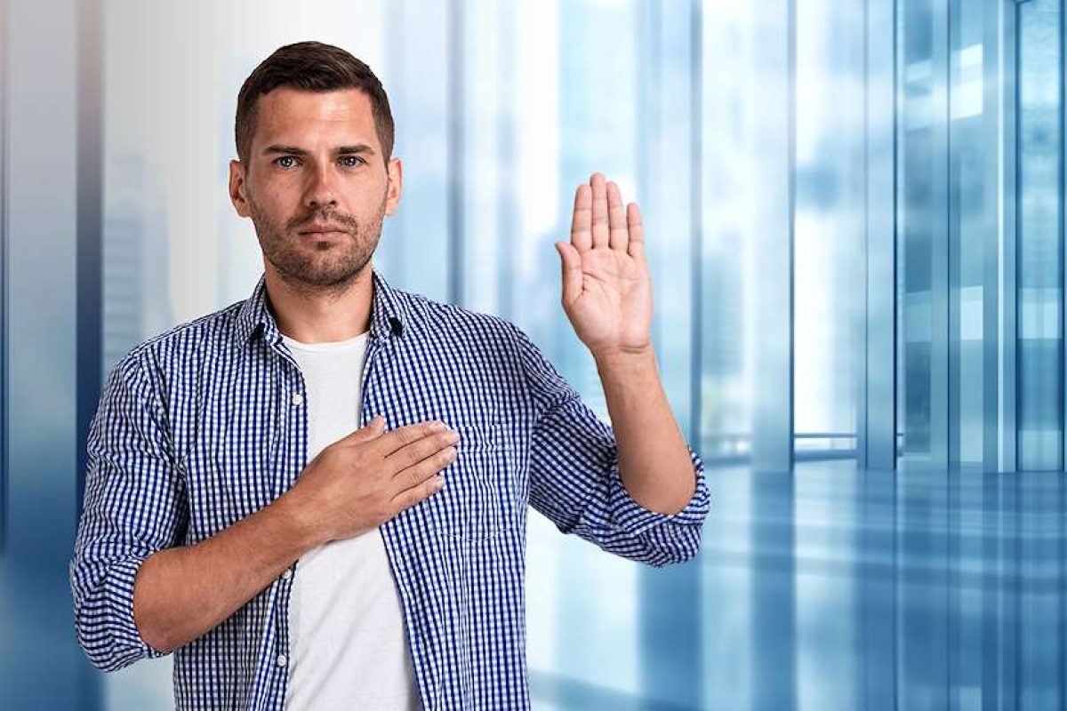 A man holding his left hand up with his right hand over his heart