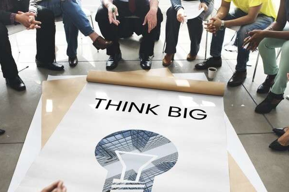 People sitting in a circle around a sign that says "Think Big"