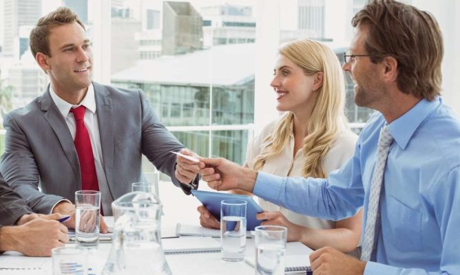 Two men passing each other a piece of paper