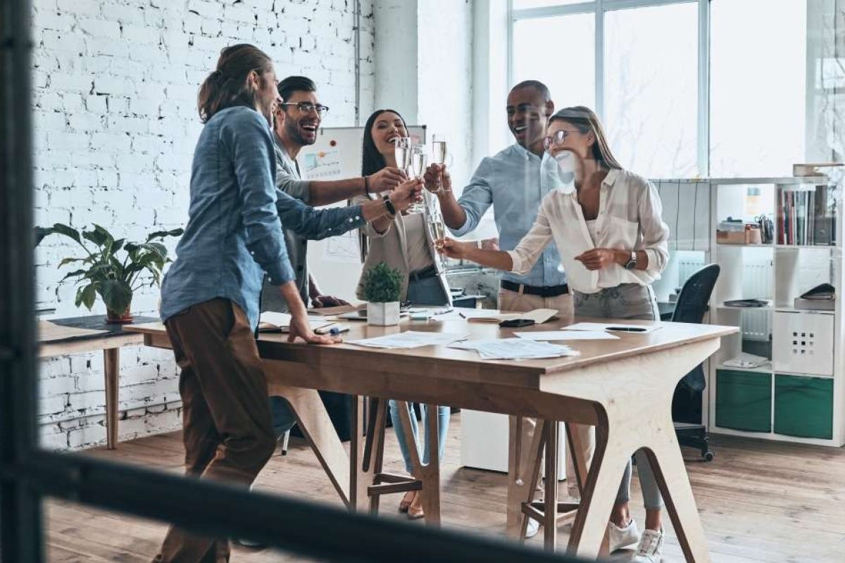 People celebrating around a work table and clinking their glasses together