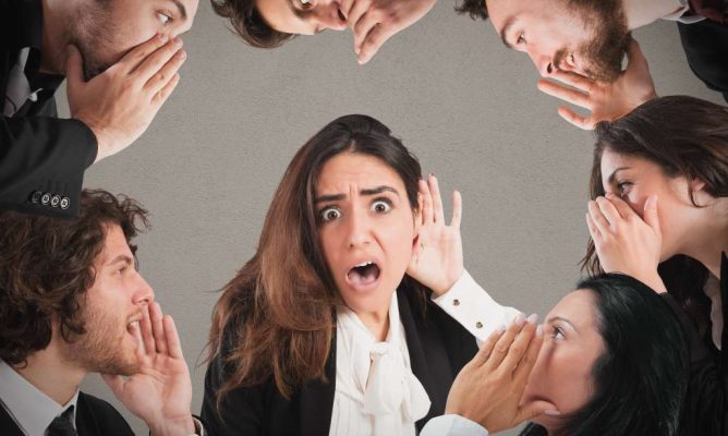 People in a circle whispering in each other's ears
