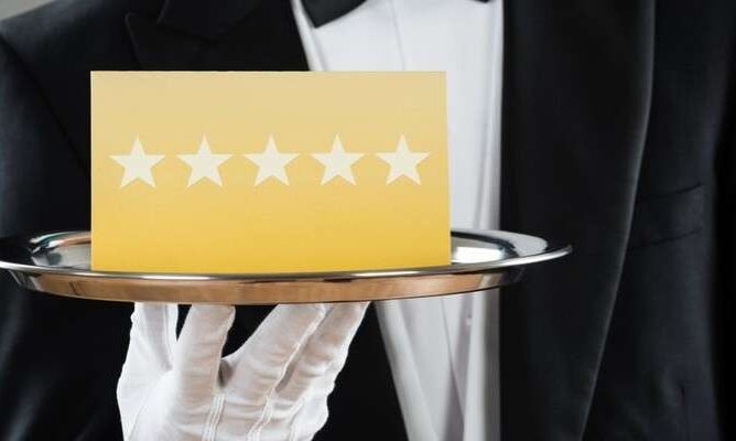 A butler holding five stars on a platter