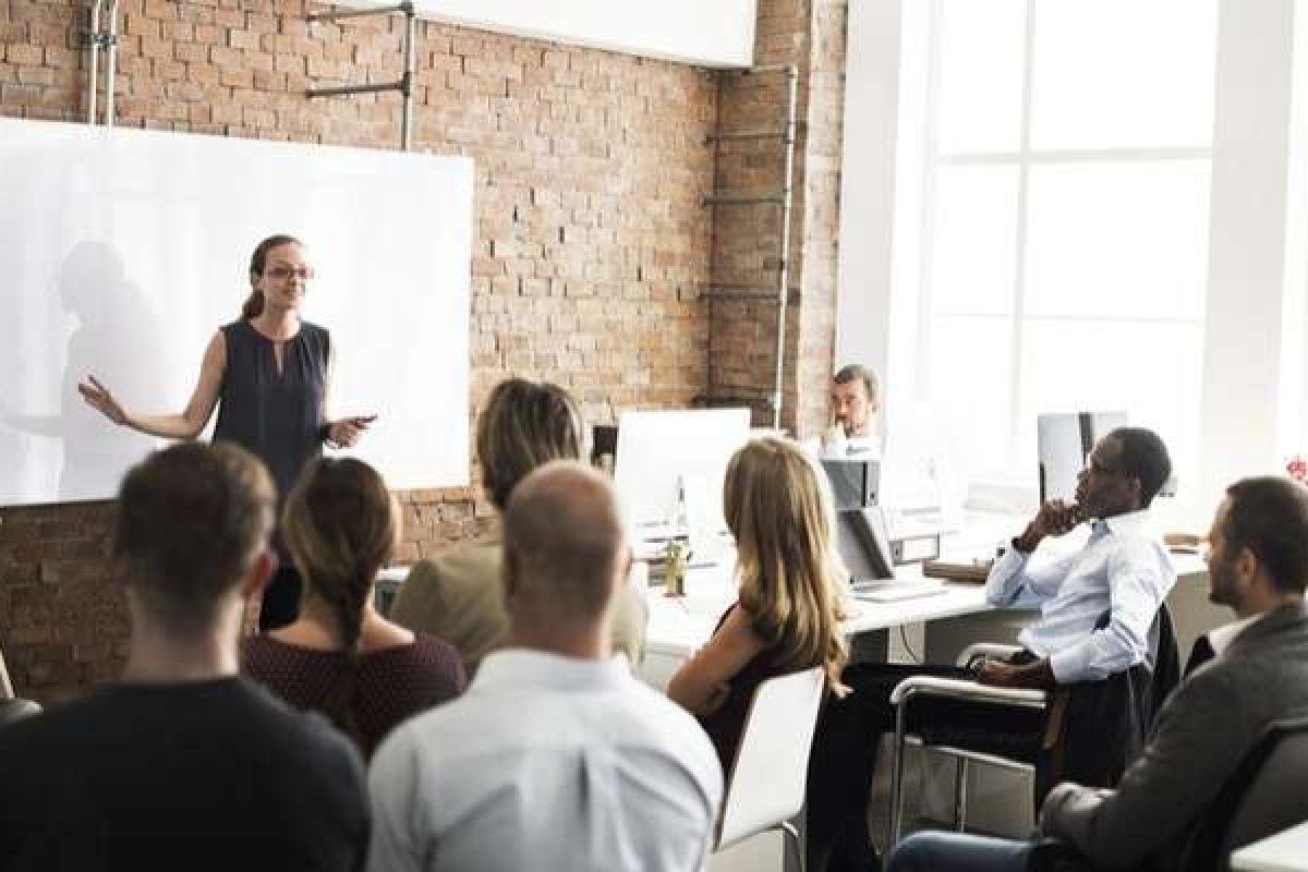 A woman delivering training at the front of the classroom